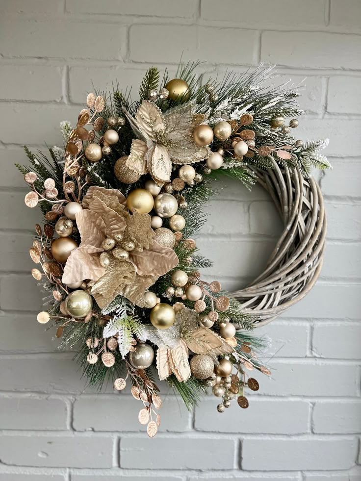 a christmas wreath on a brick wall with greenery and gold baubies hanging from it