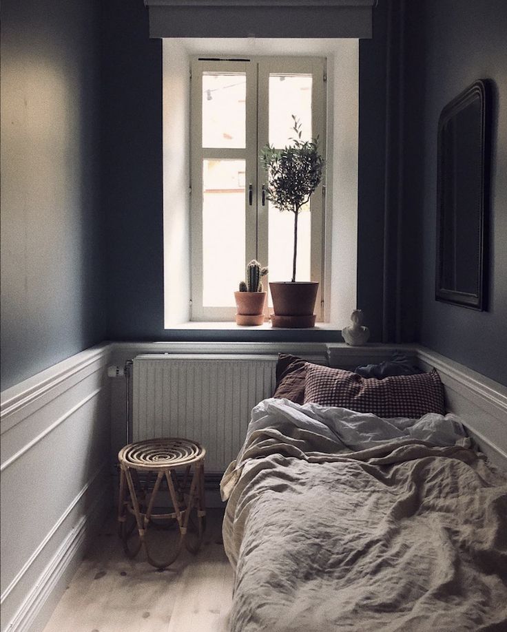 a bed sitting under a window next to a small table with a potted plant