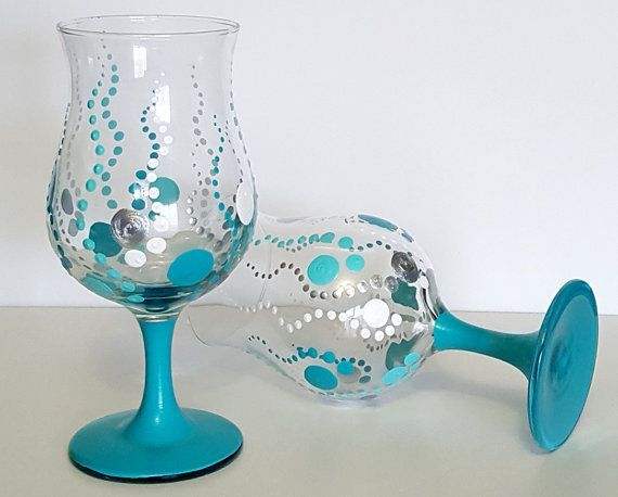 two wine glasses sitting next to each other on top of a white table with blue accents