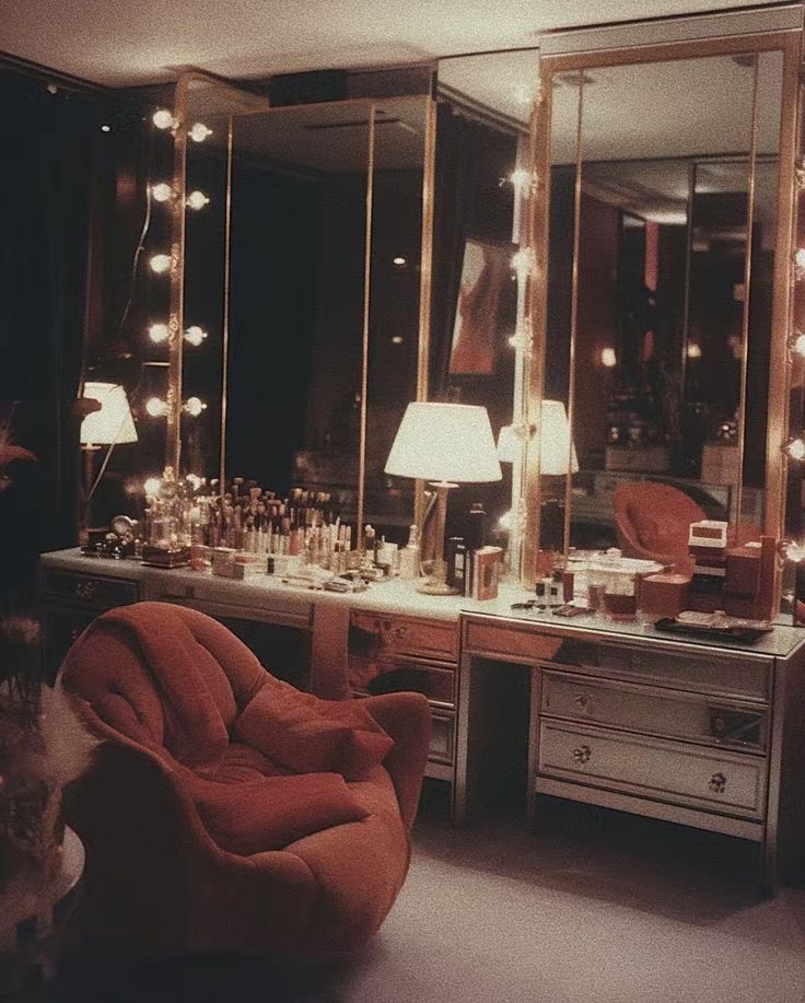 a dressing room filled with lots of vanity furniture and lighted mirrors on the wall above it