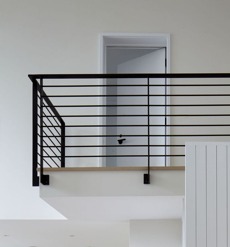 a living room with white walls and black railing