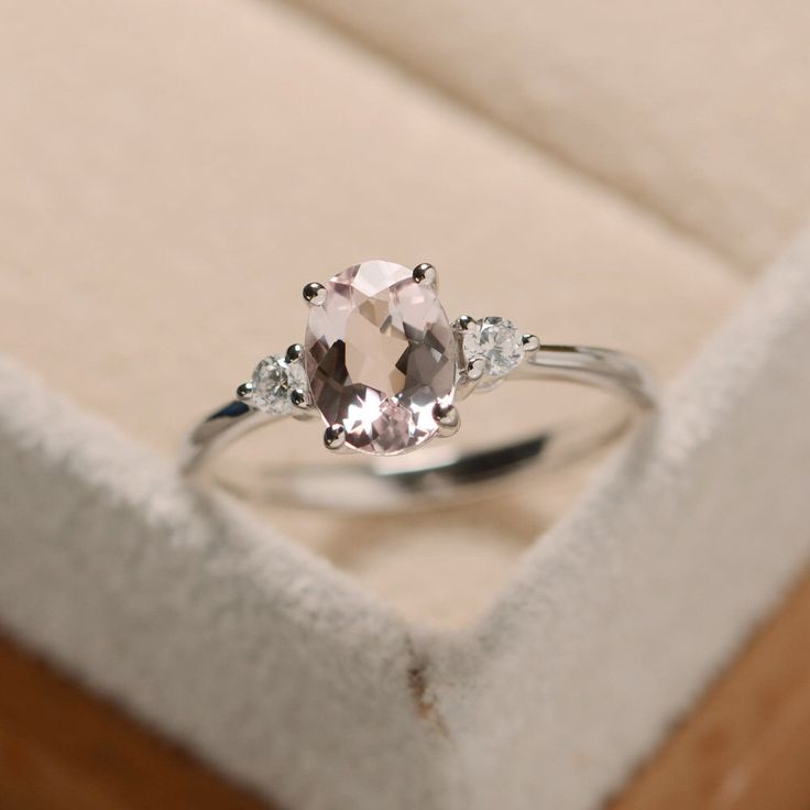 an engagement ring in a box with its lid open and two diamonds on the side