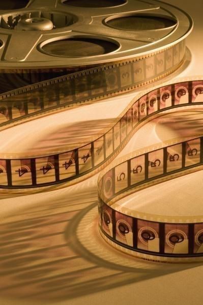 an old film reel is laying on the floor next to it's own reflection