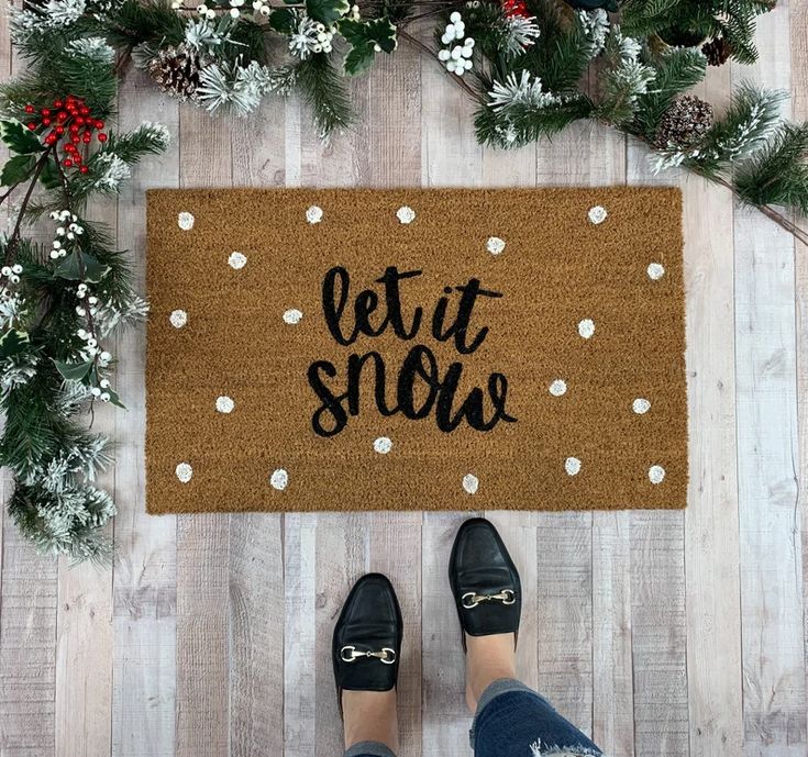 someone standing in front of a door mat that says let it snow