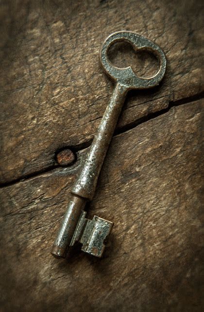 an old key is sitting on top of a piece of wood