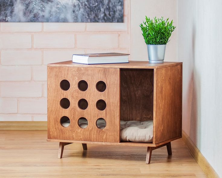 a wooden cabinet with holes in it and a potted plant next to it on a white rug