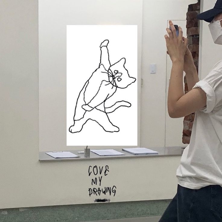 a man taking a selfie in front of a mirror with a cat drawing on it