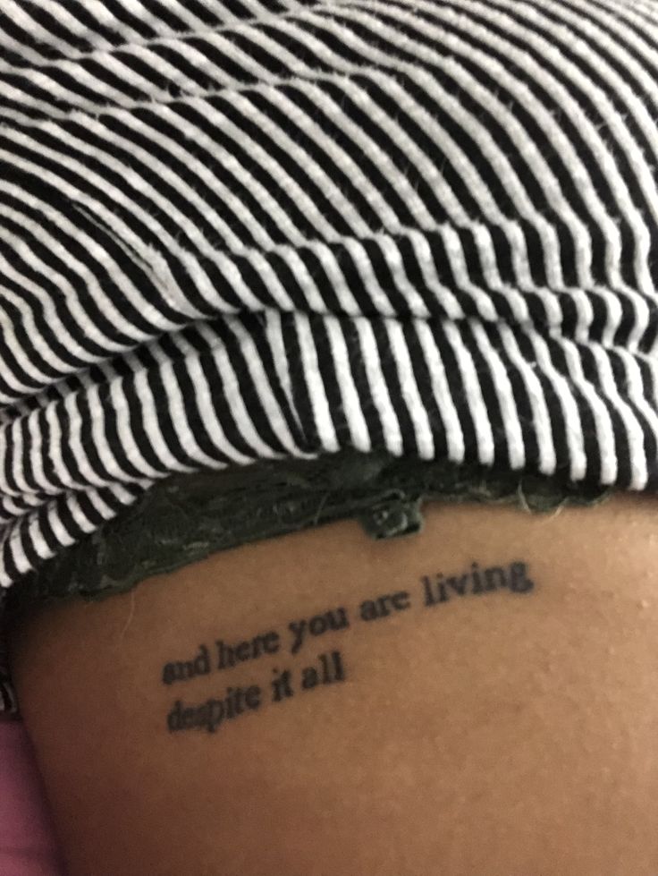 a woman with a tattoo saying and there you are living despite it all