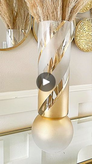 a vase filled with dried grass on top of a table next to mirrors and other decorations