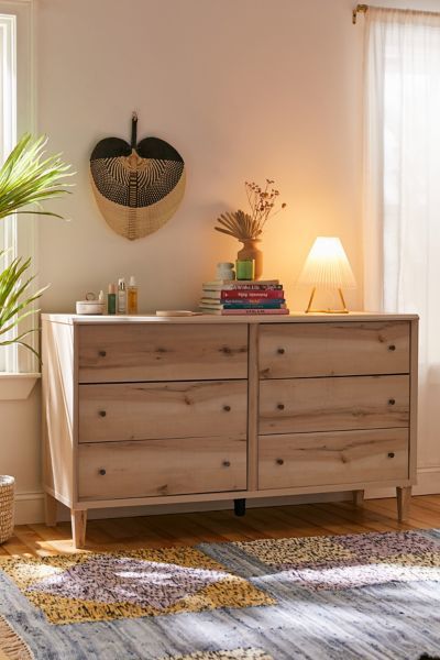 a wooden dresser sitting next to a window in a room with a rug on the floor