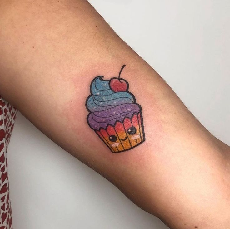 a woman's arm with a cupcake tattoo on it