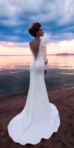 a woman standing on top of a beach next to the ocean wearing a white dress