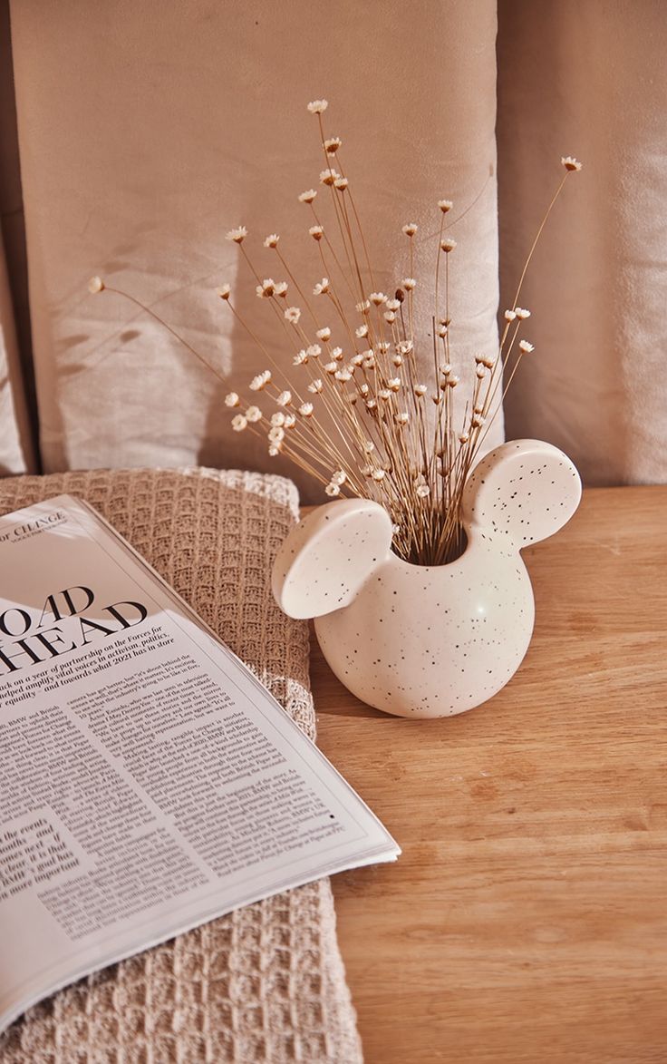 a table with a newspaper, vase and flowers on it