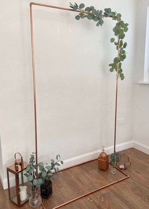 a room with white walls and wooden flooring has a gold metal frame on the wall