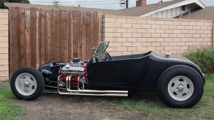 an old fashioned car is parked in front of a fence