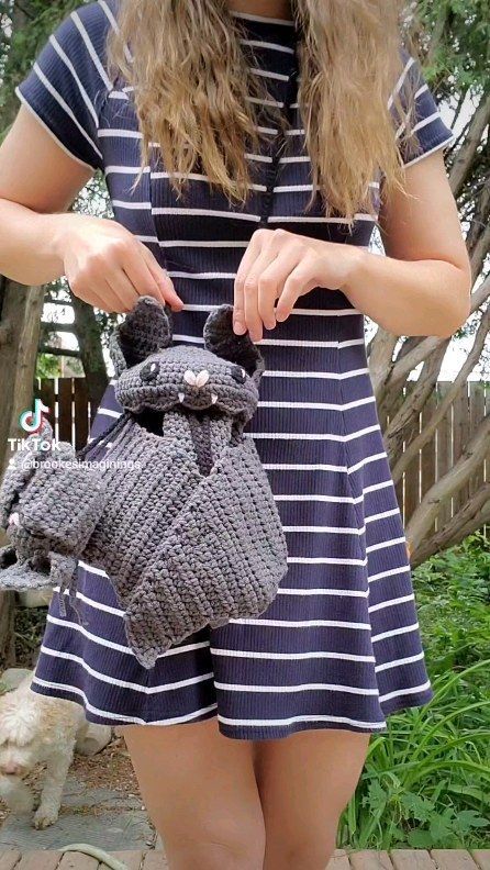 a woman in a dress holding a knitted teddy bear