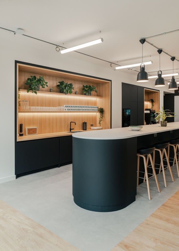 an open concept kitchen and dining area with bar stools in the foreground, built into the wall