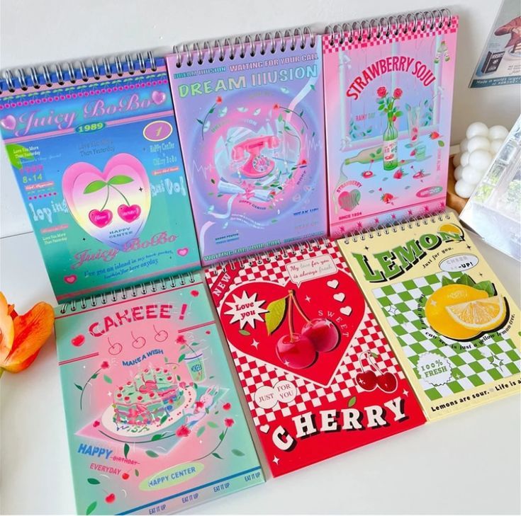 a table topped with notebooks covered in different types of greeting cards and candy bars