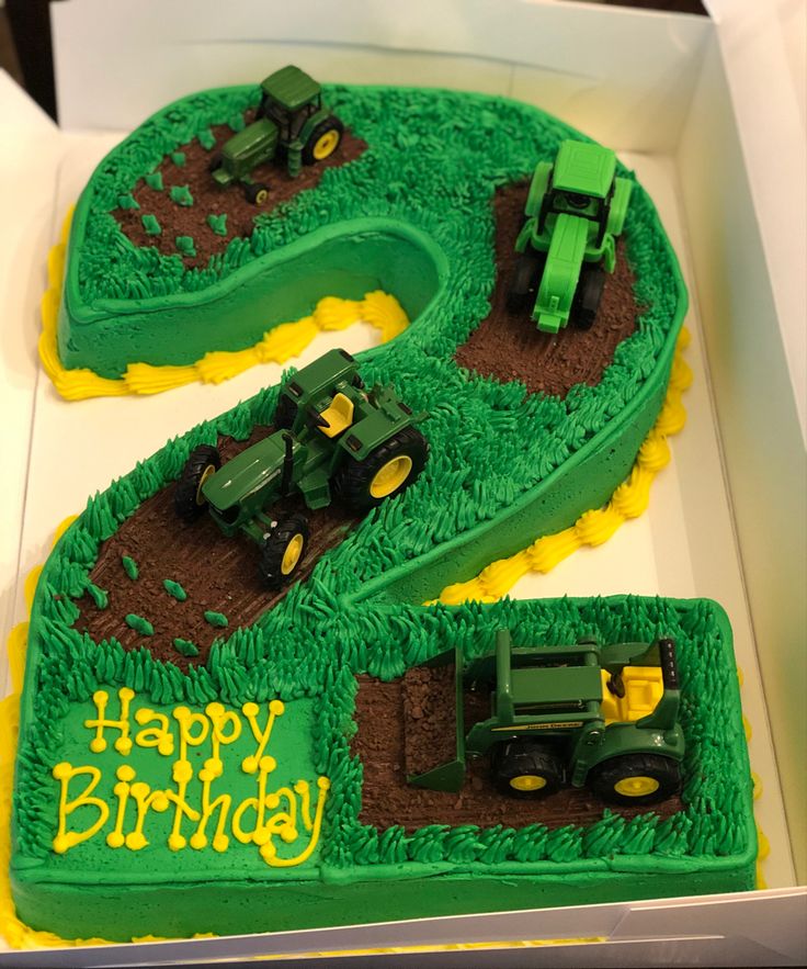 a green birthday cake with two tractors and the number six on it's side