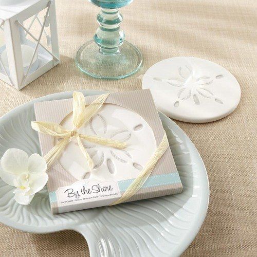 a white plate topped with a gift box on top of a table next to a candle holder