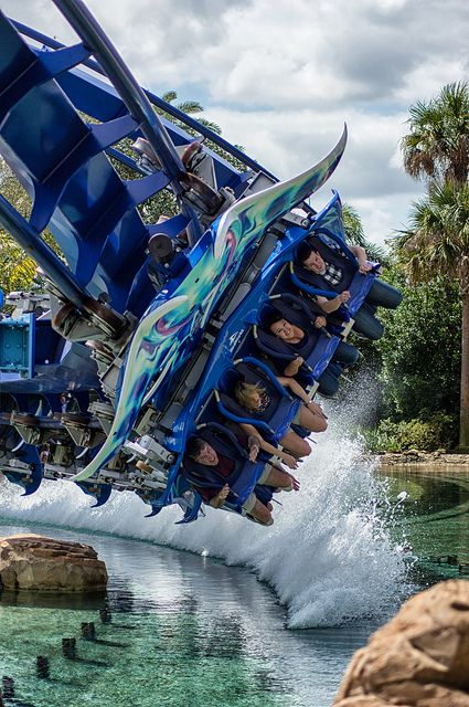 people are riding on the back of a roller coaster in an amusement park water ride