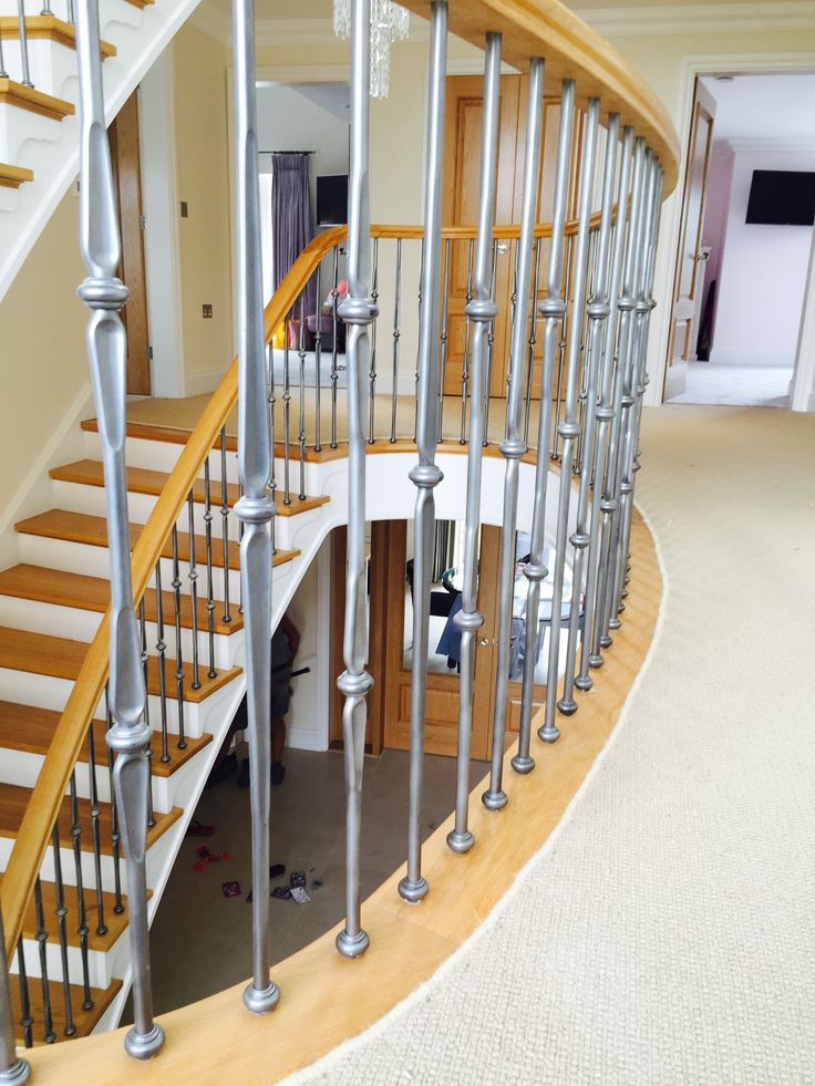 a spiral staircase in a house with white carpet and wood handrails on both sides