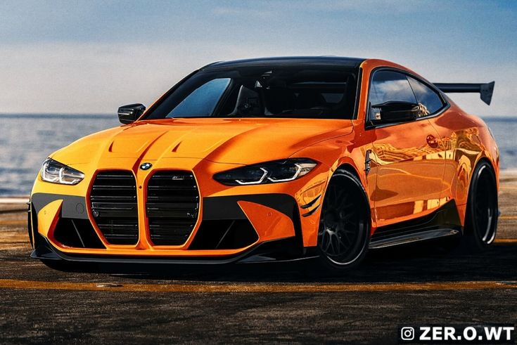 an orange sports car parked next to the ocean