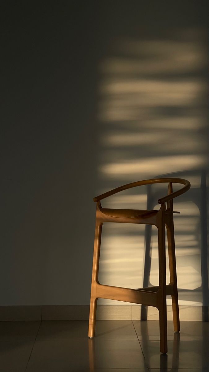 a chair sitting in the middle of a room with shadows on the wall behind it