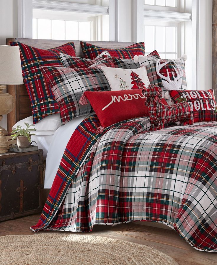 a bed with red and white plaid comforter, pillows and christmas decorations on it