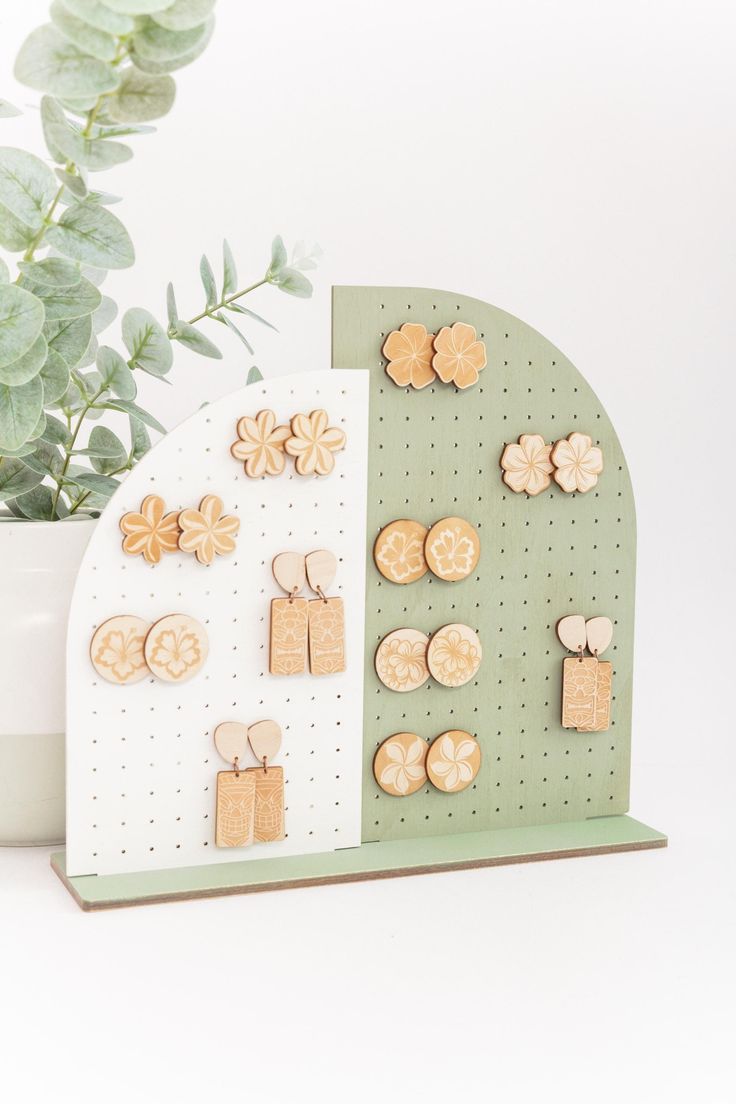 there is a plant in the vase and some wooden earrings on a pegboard next to it