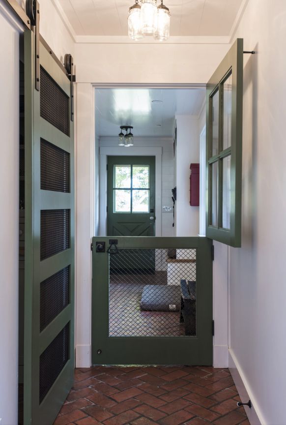 an open door leading into a hallway with brick flooring and green glass panels on the doors