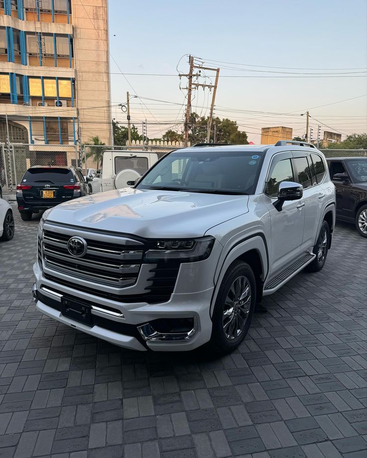 a white truck parked in front of a building on a brick road next to other cars