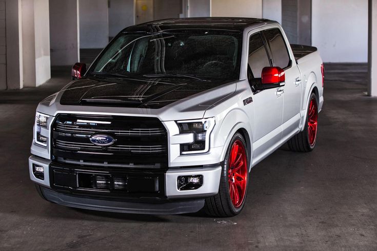 a white truck with red rims parked in a garage