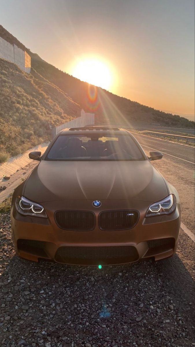 a car parked on the side of a road with the sun setting in the background