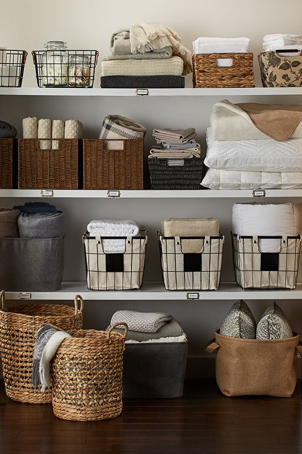 the shelves are filled with baskets, blankets and other things to put on top of them