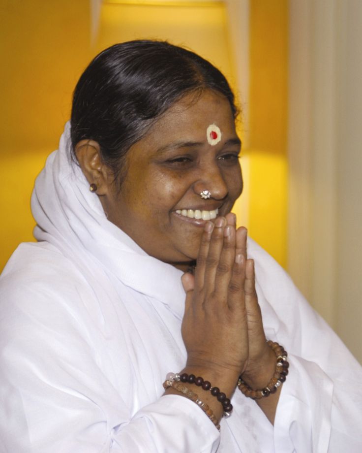 a woman with her hands together and smiling at the camera, wearing a white sari