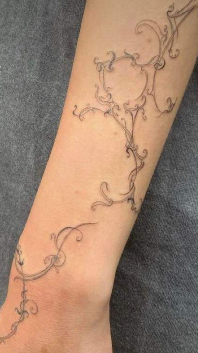 a woman's arm with an intricate vine tattoo on the left side of her arm