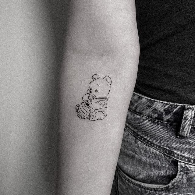 a woman's arm with a small teddy bear tattoo on it