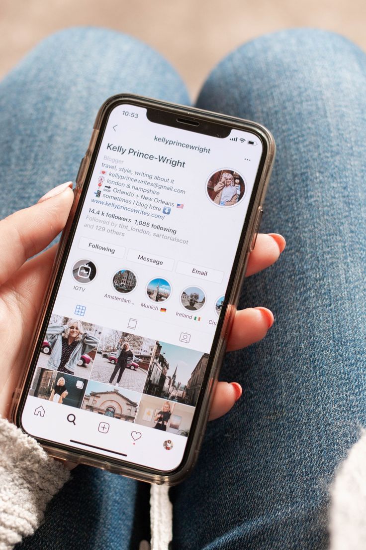 a woman holding up her phone with the facebook page displayed on it's screen