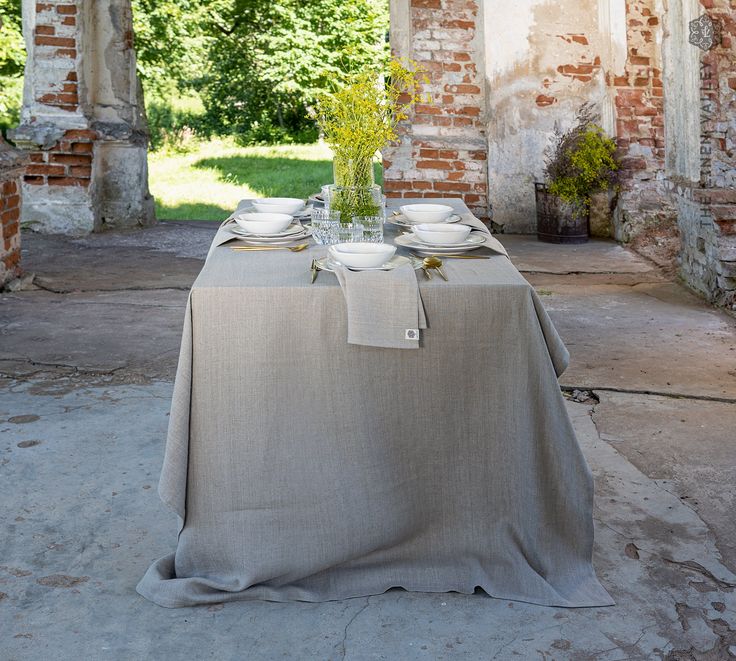 the table is set with plates and silverware on it, in front of an old brick building