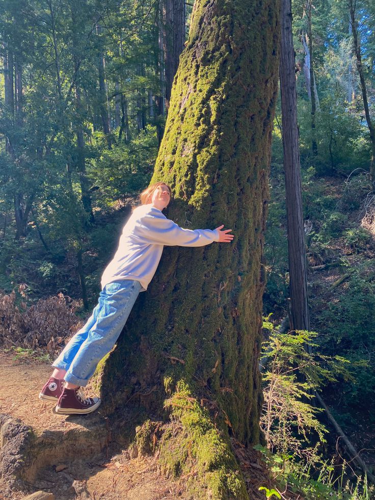 a young boy leaning against a tree in the woods