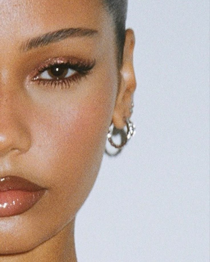 a close up shot of a woman's face with earrings on her head and one eye open