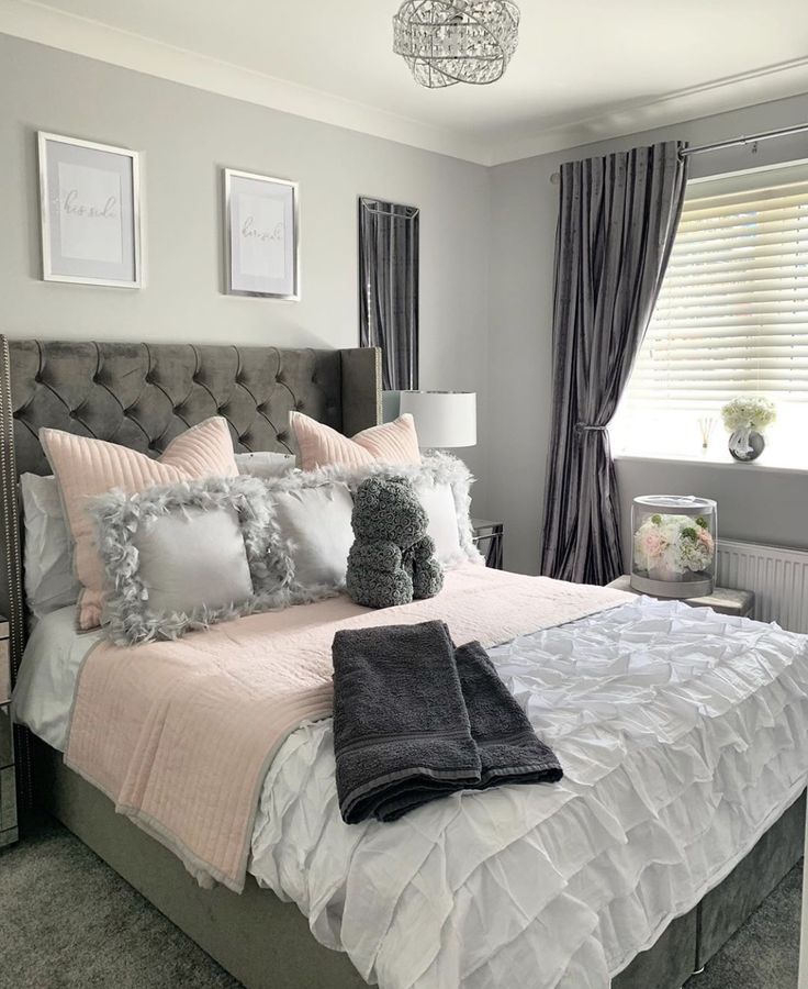 a bed with pillows and blankets on top of it in a bedroom next to a window