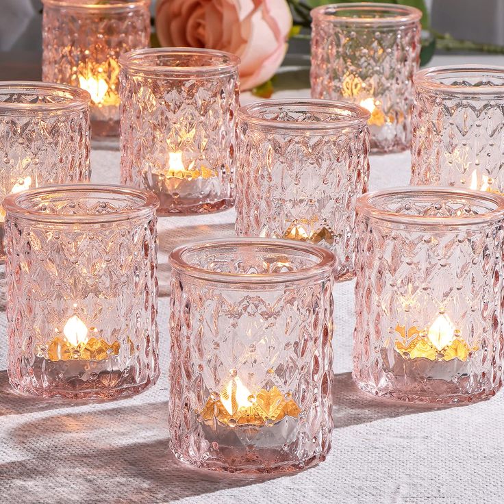 there are many glass jars with candles in them