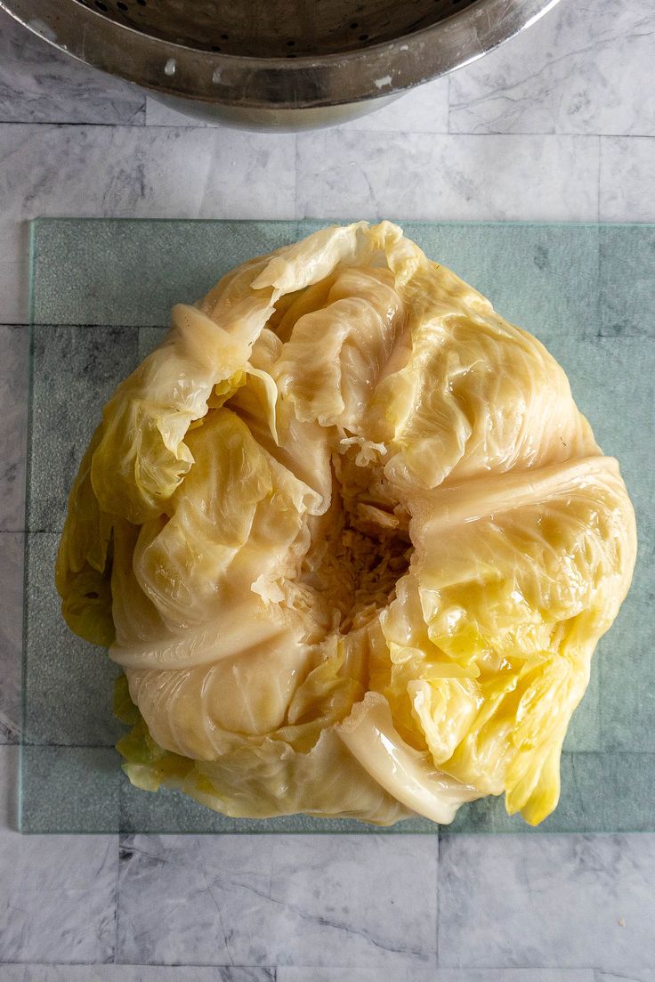 a head of cabbage sitting on top of a glass cutting board next to a pot