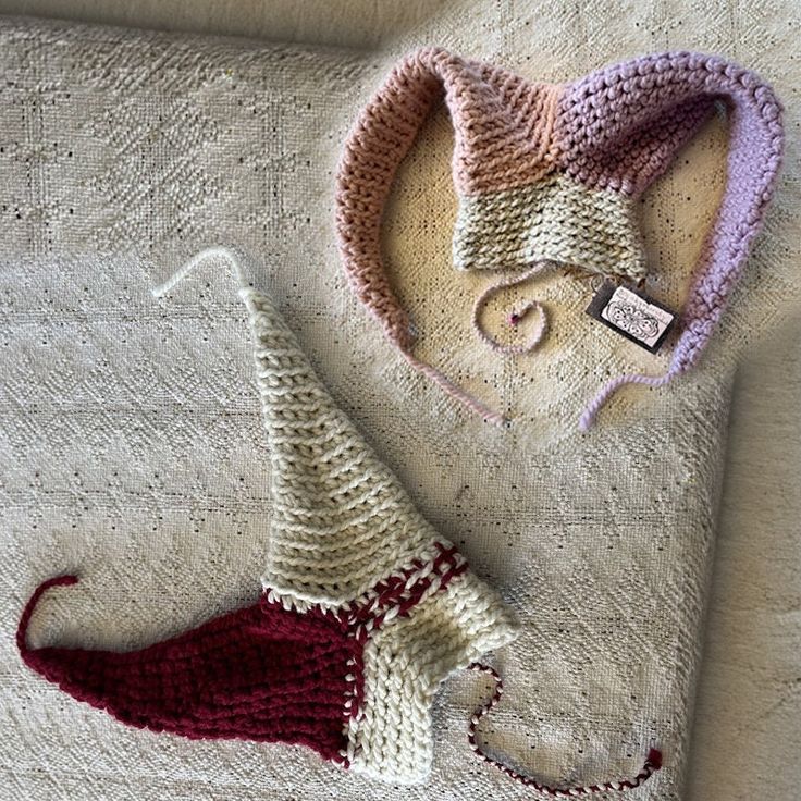 two crocheted hats laying on top of a white blanket