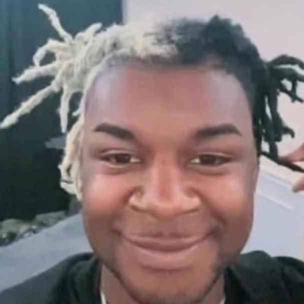 a man with dreadlocks smiles at the camera