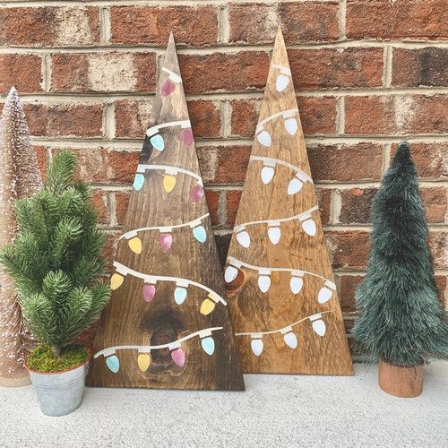 three wooden christmas trees sitting next to each other on top of a shelf in front of a brick wall