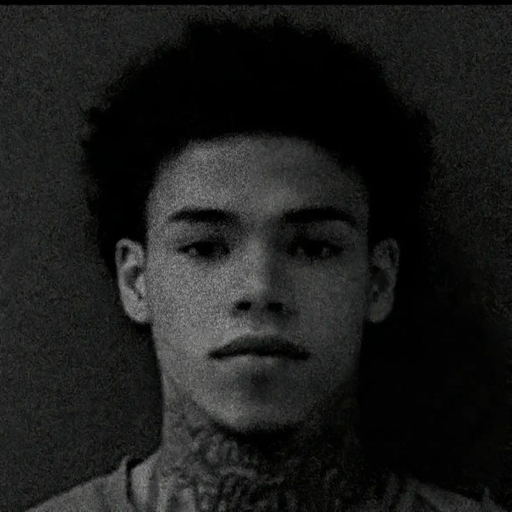 black and white photograph of a young man with tattoos on his neck looking at the camera