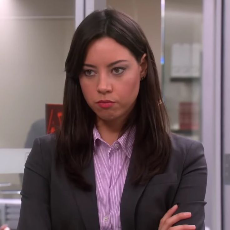 a woman with her arms crossed standing in an office